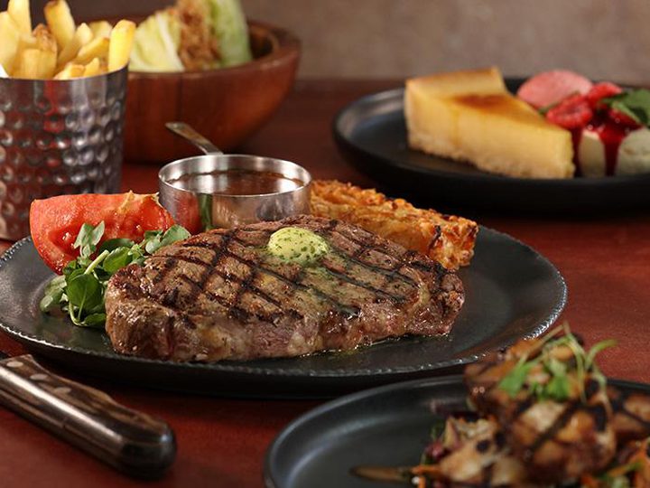 Grilled steak with butter, lettuce wedge and sides