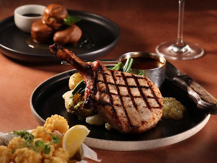 Grilled pork tomahawk with calamari and sides